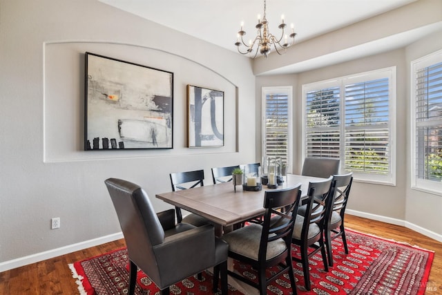 dining space with baseboards, a chandelier, and wood finished floors