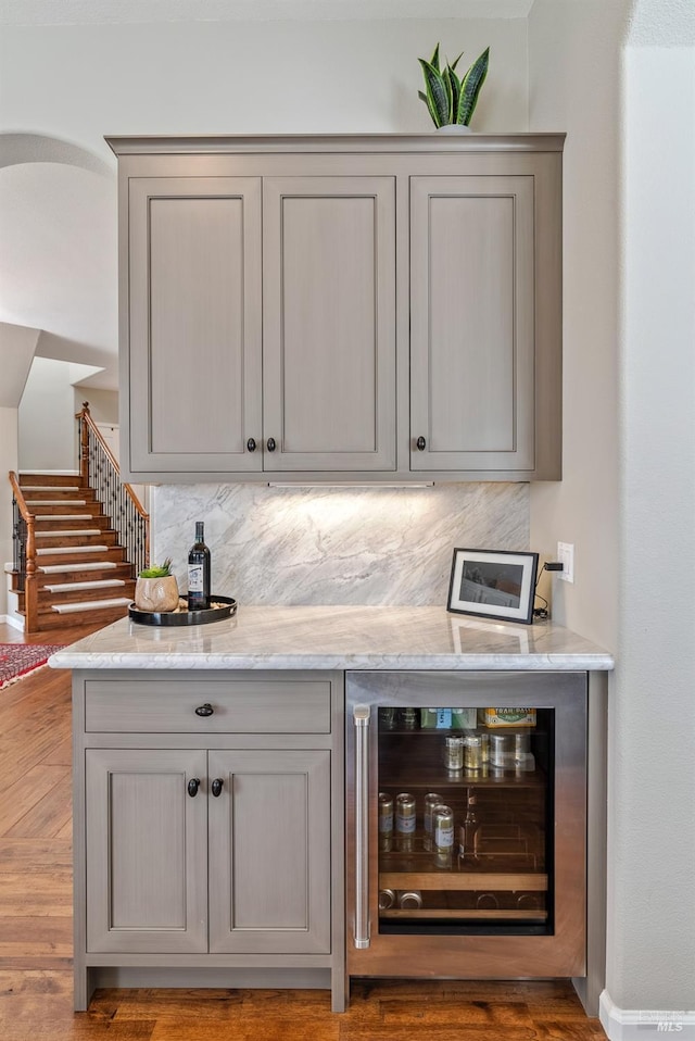 bar with a bar, backsplash, wine cooler, and stairway