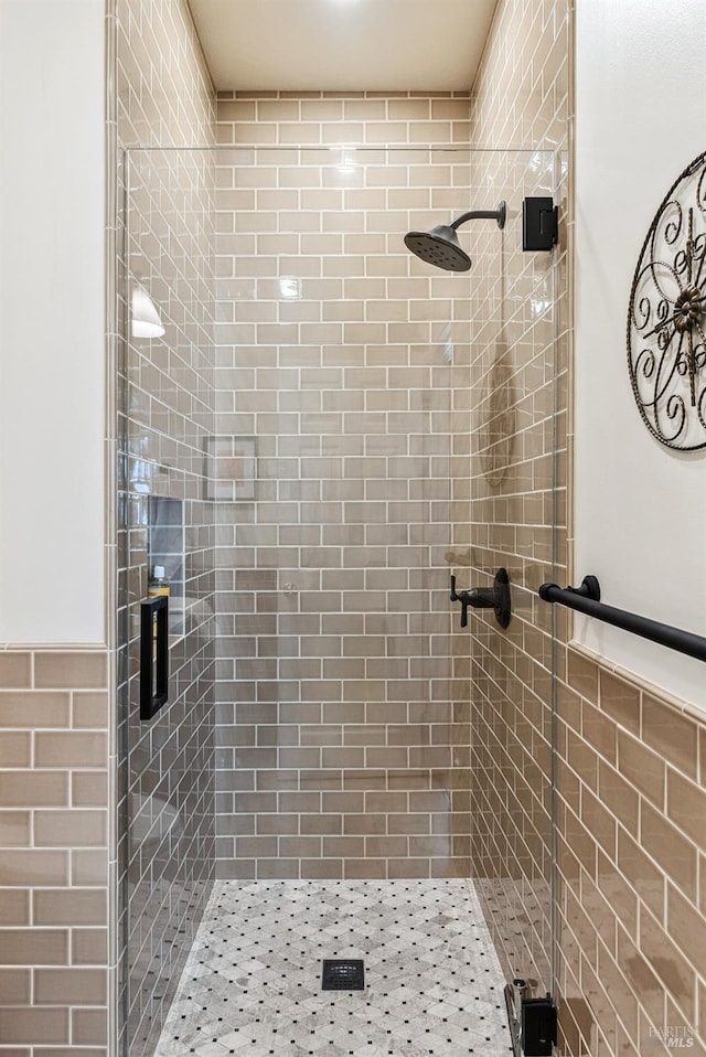bathroom with a stall shower, tile walls, and wainscoting
