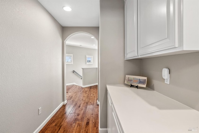 interior space featuring arched walkways, baseboards, and hardwood / wood-style flooring