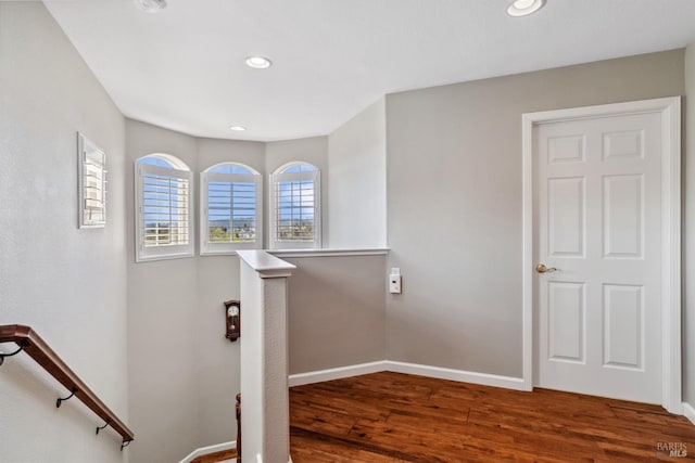 stairway featuring baseboards, wood finished floors, and recessed lighting
