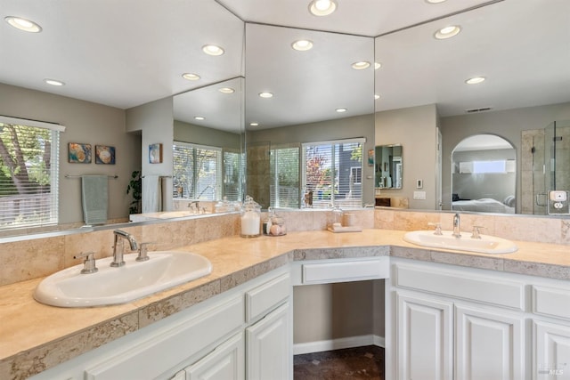 ensuite bathroom with ensuite bathroom, plenty of natural light, and a sink