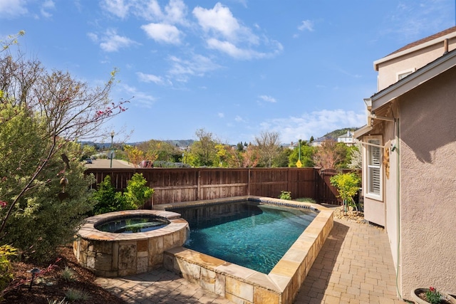view of swimming pool featuring a fenced backyard, a pool with connected hot tub, and a patio