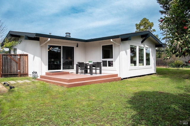 rear view of house with a lawn, fence, and a wooden deck