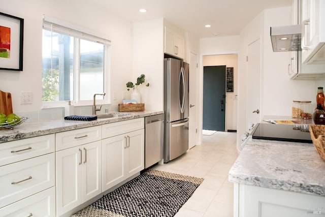 kitchen featuring light stone countertops, stainless steel appliances, white cabinetry, a sink, and recessed lighting