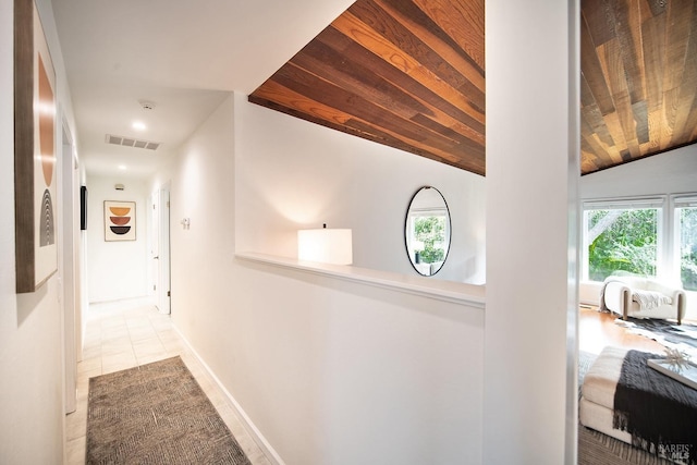 hallway featuring visible vents, wood ceiling, vaulted ceiling, tile patterned flooring, and baseboards