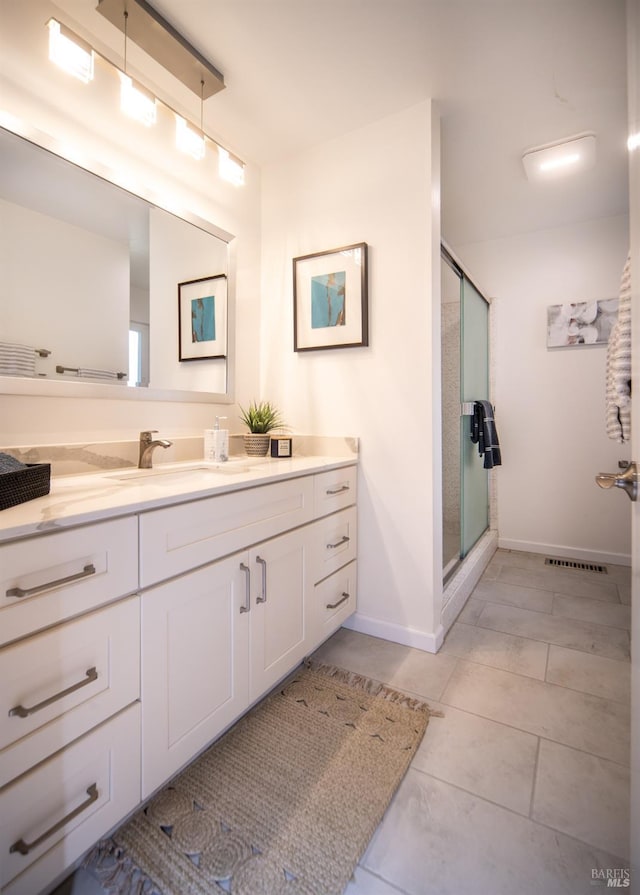 bathroom featuring a stall shower, vanity, baseboards, and tile patterned floors