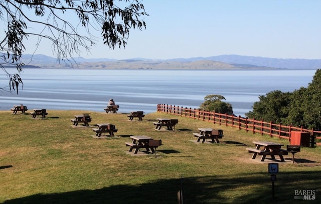 surrounding community with a yard, fence, and a water and mountain view