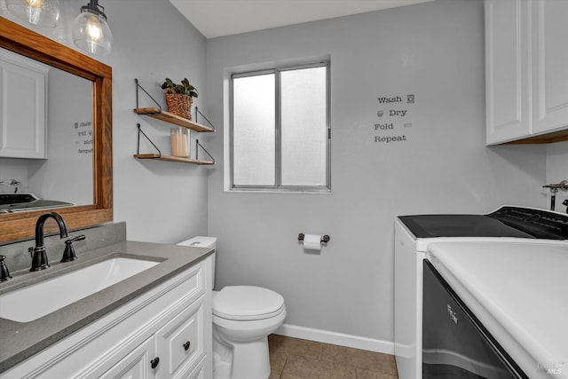 bathroom with independent washer and dryer, vanity, toilet, tile patterned floors, and baseboards