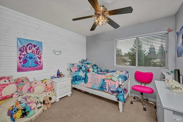 carpeted bedroom featuring ceiling fan and wooden walls