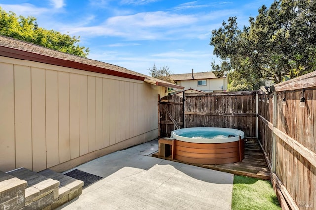 view of patio with a hot tub and fence