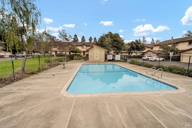 pool featuring fence, a patio, and a residential view
