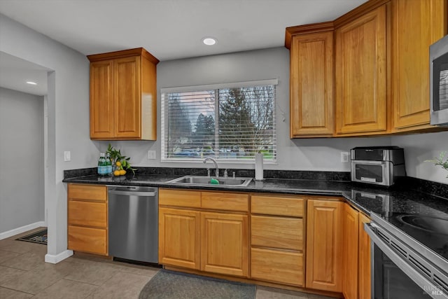 kitchen featuring a sink, dark stone counters, stainless steel appliances, recessed lighting, and light tile patterned floors