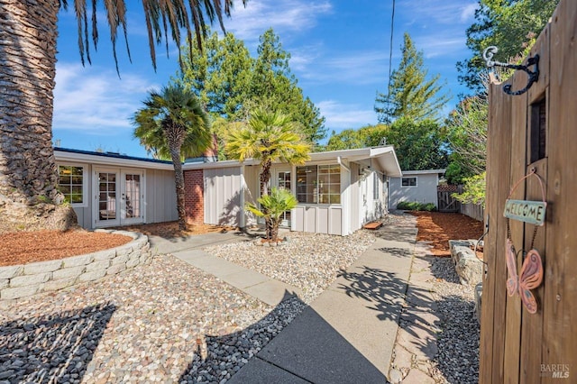 rear view of property with french doors, brick siding, and fence