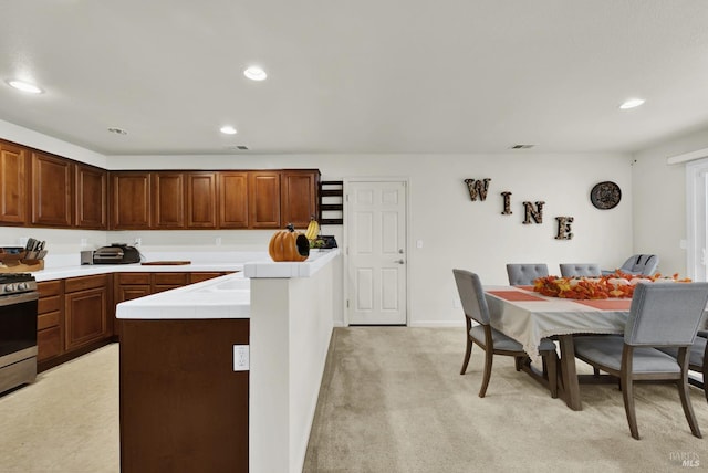 kitchen featuring tile countertops, recessed lighting, visible vents, light colored carpet, and stainless steel gas range oven