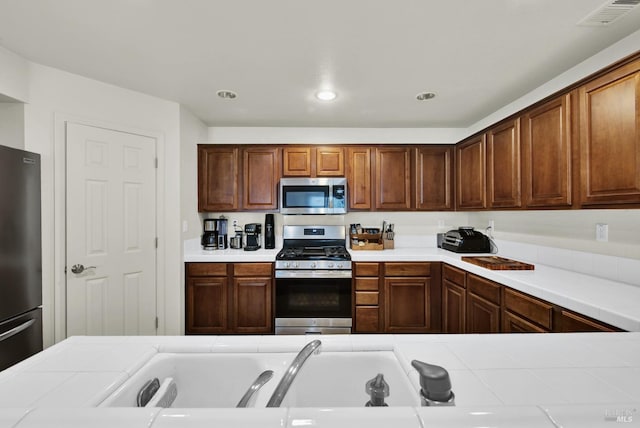 kitchen with tile countertops, stainless steel appliances, visible vents, and recessed lighting