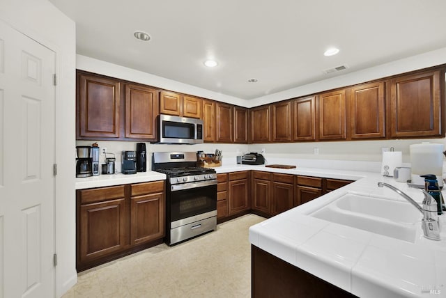 kitchen with stainless steel appliances, tile counters, recessed lighting, visible vents, and a sink