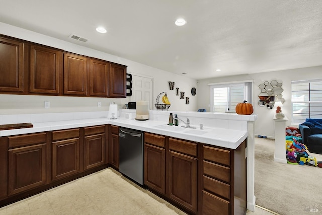 kitchen with a peninsula, a sink, visible vents, open floor plan, and dishwasher