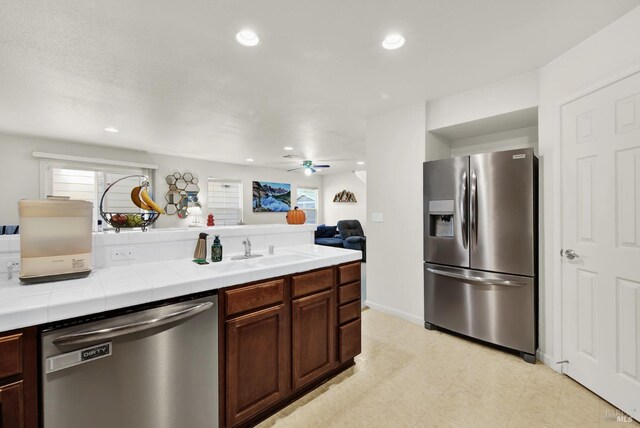 kitchen with stainless steel appliances, a sink, tile counters, and recessed lighting