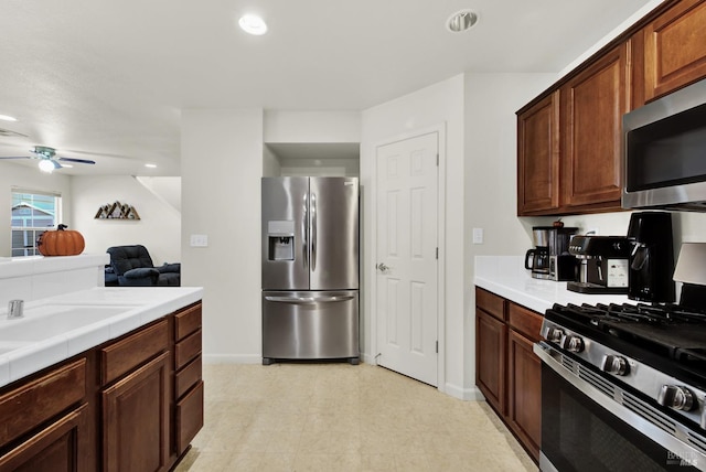 kitchen featuring a ceiling fan, tile countertops, appliances with stainless steel finishes, light floors, and recessed lighting