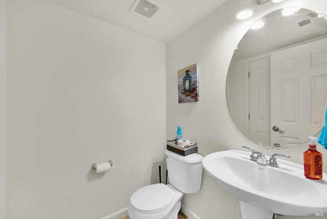 bathroom featuring baseboards, visible vents, a sink, and toilet