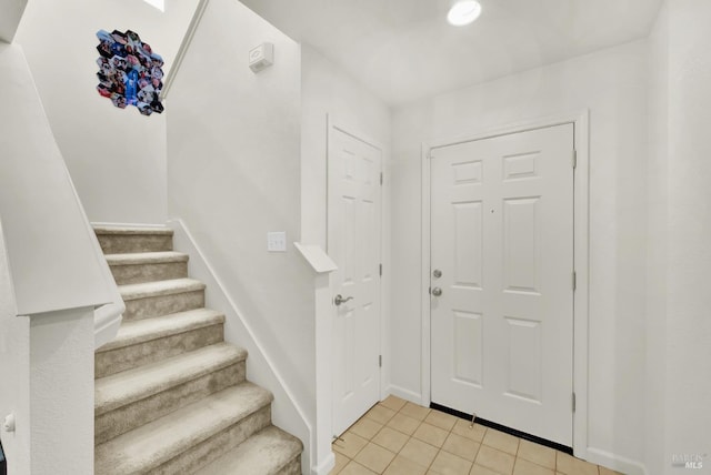 foyer featuring stairs, baseboards, and light tile patterned flooring