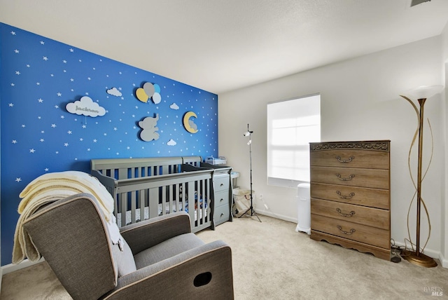 bedroom featuring a crib, wallpapered walls, baseboards, an accent wall, and carpet floors