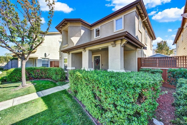 view of front facade featuring fence, a front lawn, and stucco siding