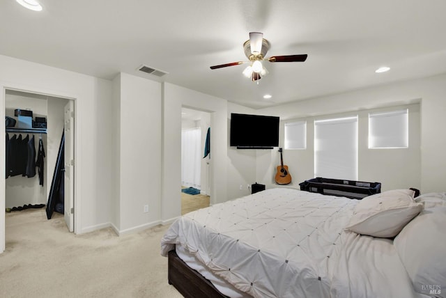 bedroom featuring a walk in closet, recessed lighting, a closet, light carpet, and baseboards