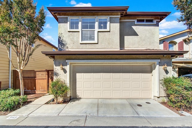 view of front of property featuring a garage, driveway, fence, and stucco siding