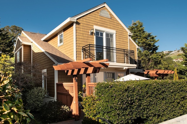 view of side of property featuring roof with shingles and a balcony