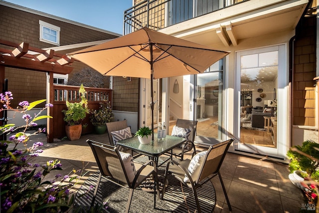 view of patio / terrace with a balcony, outdoor dining area, and a pergola