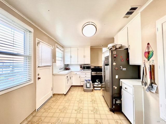 kitchen featuring visible vents, white cabinets, stainless steel appliances, light countertops, and light floors