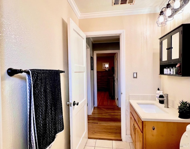 bathroom featuring tile patterned flooring, visible vents, crown molding, and vanity