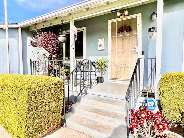 doorway to property with covered porch and stucco siding