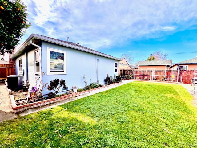 exterior space featuring cooling unit, a fenced backyard, a yard, and stucco siding