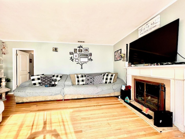 living room featuring a fireplace, wood finished floors, visible vents, and crown molding