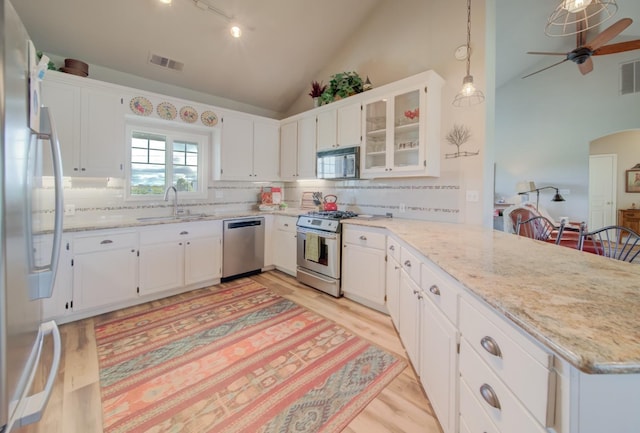 kitchen featuring vaulted ceiling, a sink, a peninsula, stainless steel appliances, and visible vents