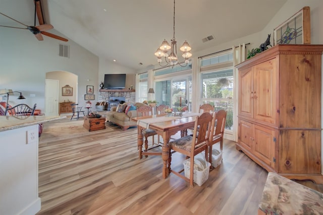 dining room with light wood-style flooring, ceiling fan with notable chandelier, visible vents, and arched walkways