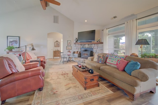 living area with wood finished floors, arched walkways, ceiling fan, and visible vents