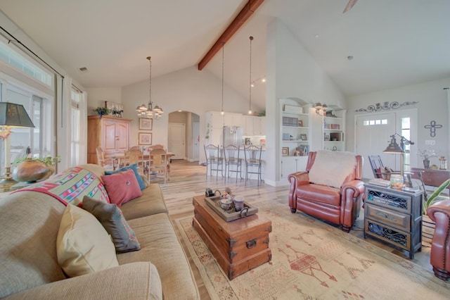living room with high vaulted ceiling, wood finished floors, beam ceiling, arched walkways, and a notable chandelier