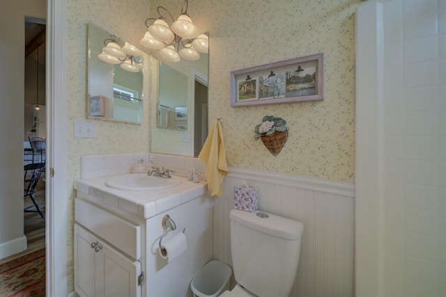bathroom featuring wallpapered walls, toilet, a chandelier, and wainscoting
