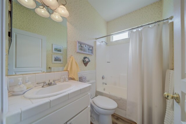 bathroom with wallpapered walls, toilet, vanity, an inviting chandelier, and wainscoting