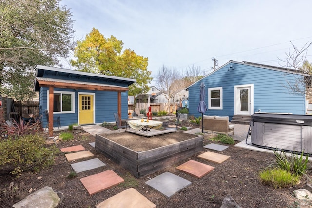 exterior space featuring an outdoor structure, fence, a vegetable garden, and a hot tub