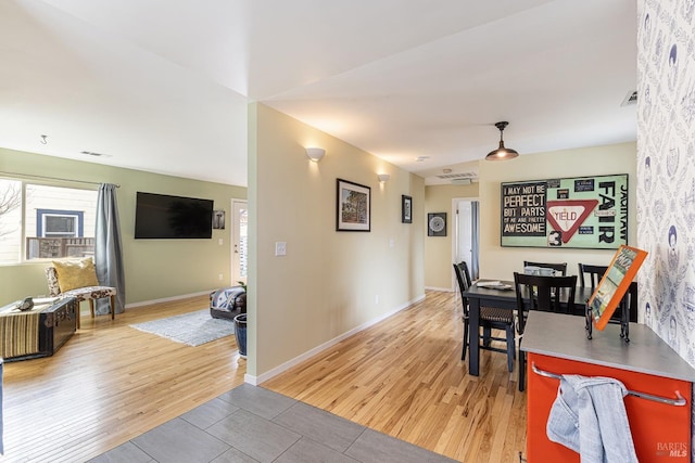 dining area with visible vents, light wood-style flooring, and baseboards