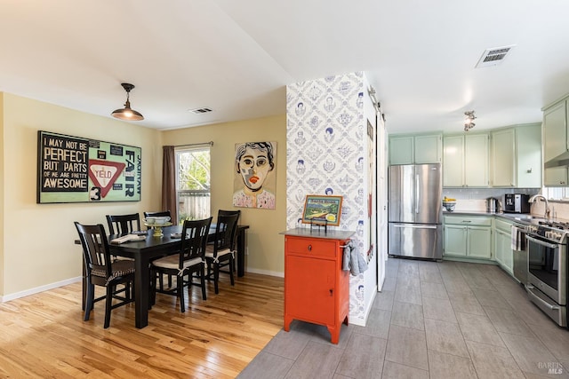 dining room featuring light wood-type flooring, baseboards, and visible vents