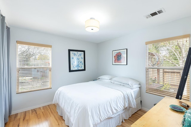 bedroom featuring light wood-type flooring, visible vents, and baseboards