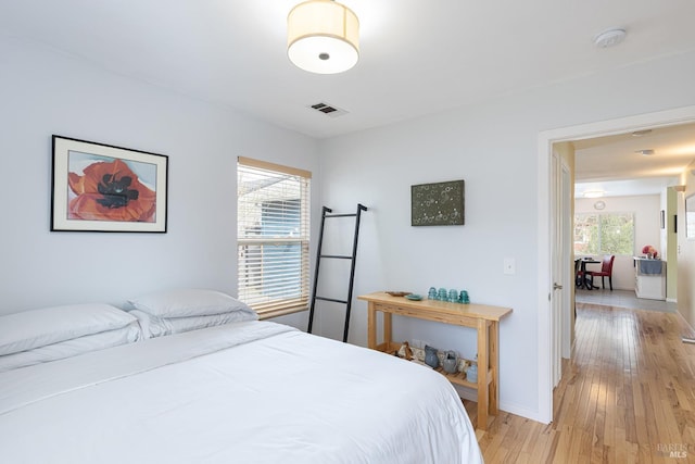 bedroom featuring light wood-style floors, multiple windows, visible vents, and baseboards