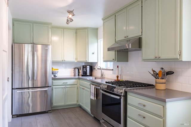 kitchen with tasteful backsplash, appliances with stainless steel finishes, under cabinet range hood, a sink, and light tile patterned flooring