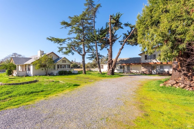 view of front of property with driveway, a chimney, and a front lawn